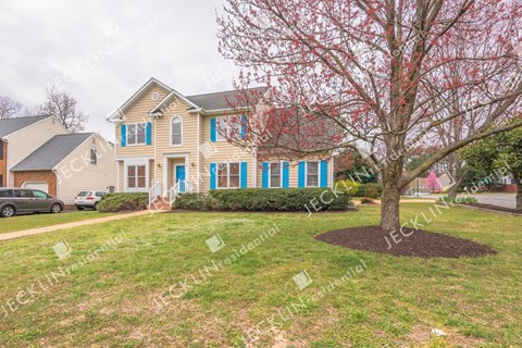 A house with blue shutters and a tree in the front yard.