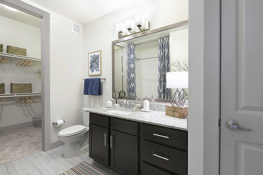 a bathroom with black cabinets and a mirror and a toilet