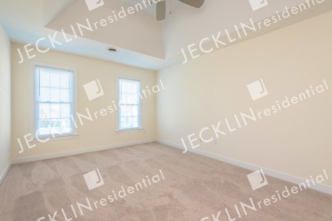 an empty living room with a ceiling fan and two windows