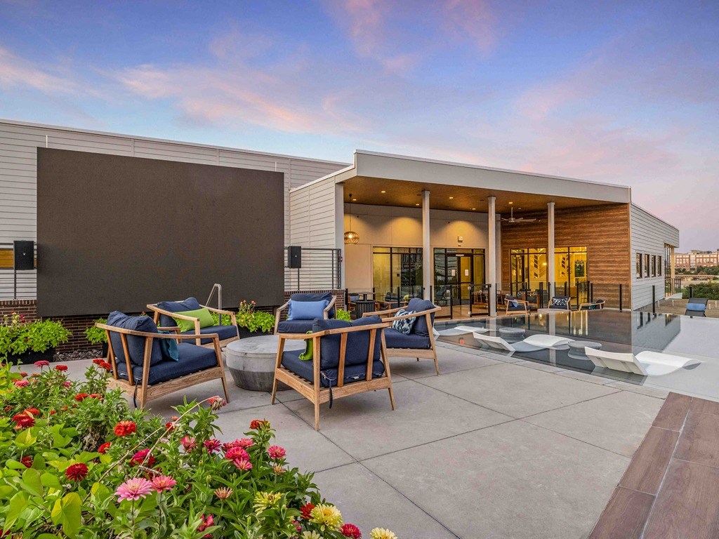 a patio with chairs and a pool in front of a building