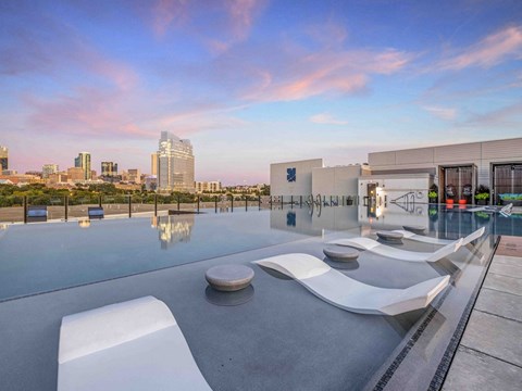 a rooftop pool with lounge chairs and a view of the city