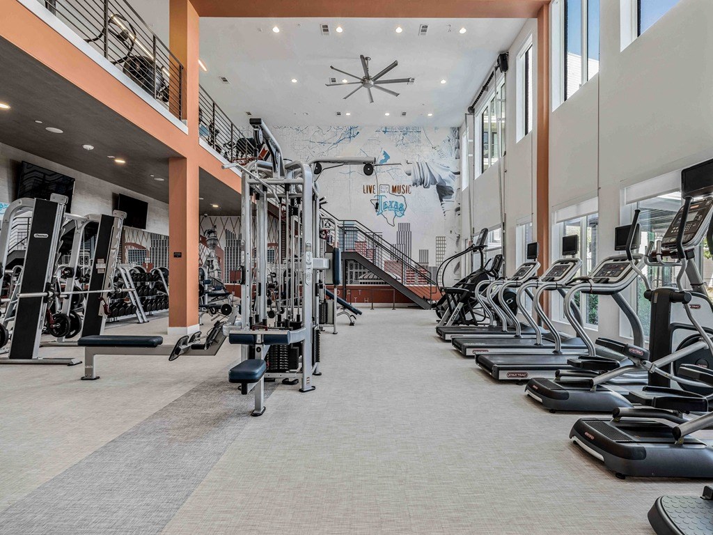 a gym with cardio equipment and a mural on the wall