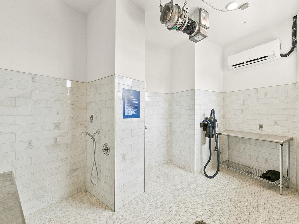a large white tiled bathroom with a shower and a sink