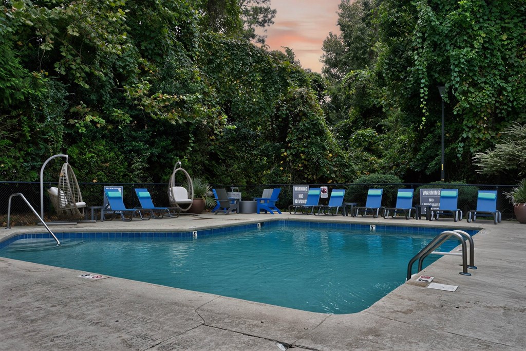 A pool surrounded by trees and chairs.at Lofts of Wilmington, North Carolina, 28405