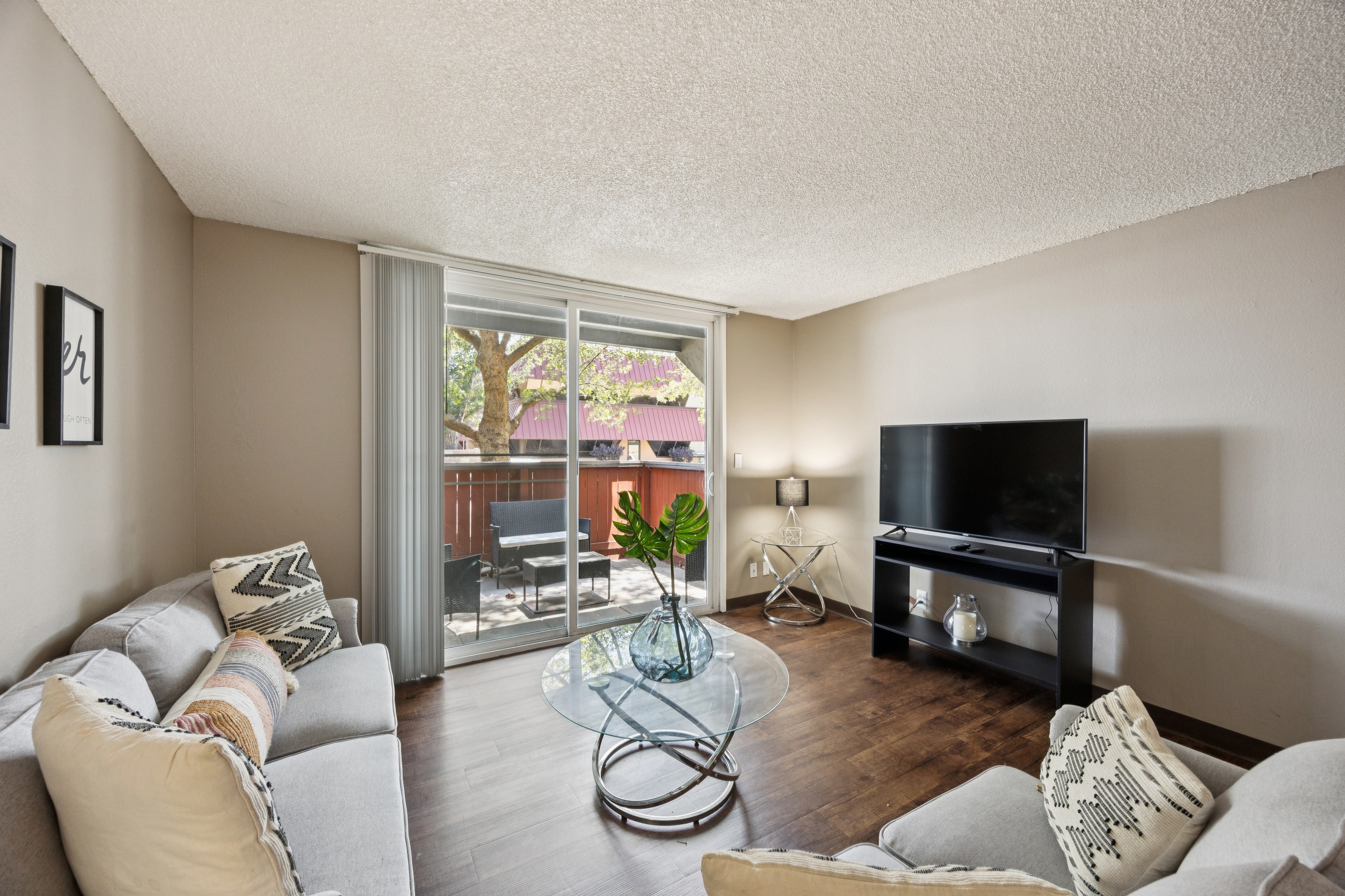 A living room with a grey couch and a glass coffee table.
