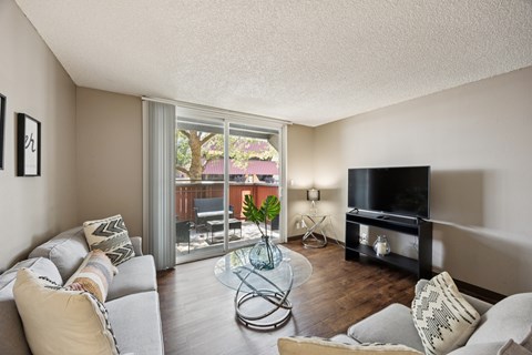 A living room with a grey couch and a glass coffee table.