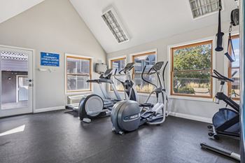 A gym with a variety of equipment including treadmills, stationary bikes, and weights.