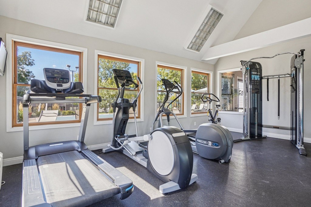 A home gym with a treadmill, elliptical trainer, and other exercise equipment.