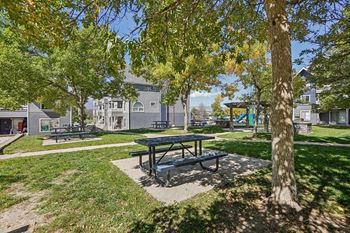 A park with a picnic table and a tree in the foreground.