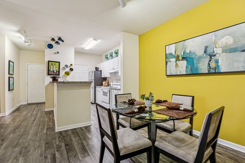 A dining room with a table set for two and a painting on the wall.