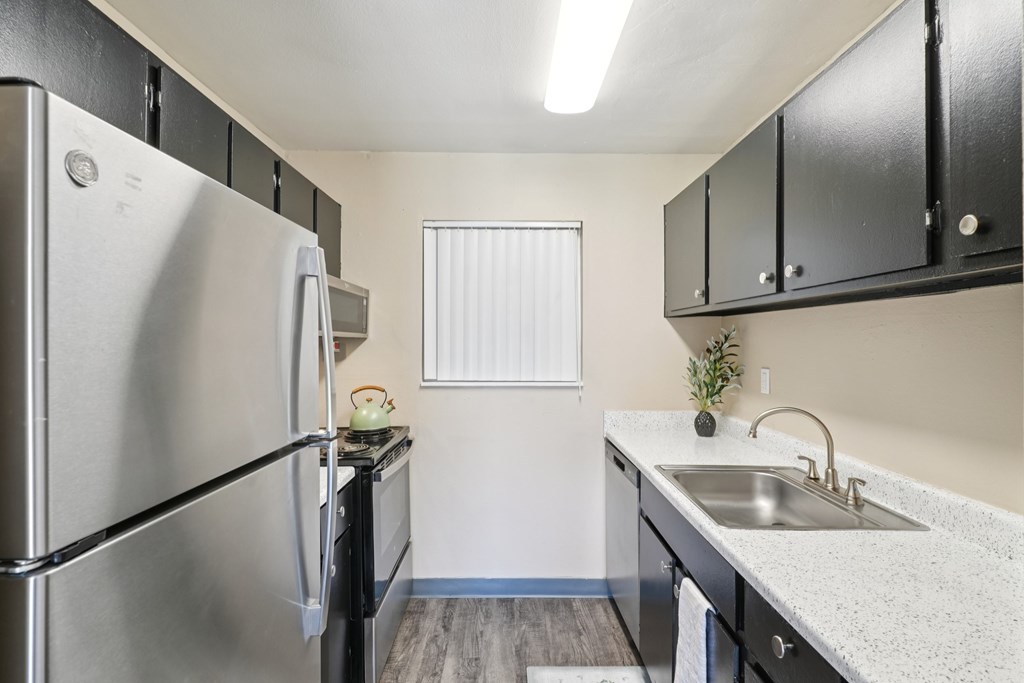 A kitchen with a stainless steel refrigerator and black cabinets. at Broadmoor Springs, Colorado Springs, CO