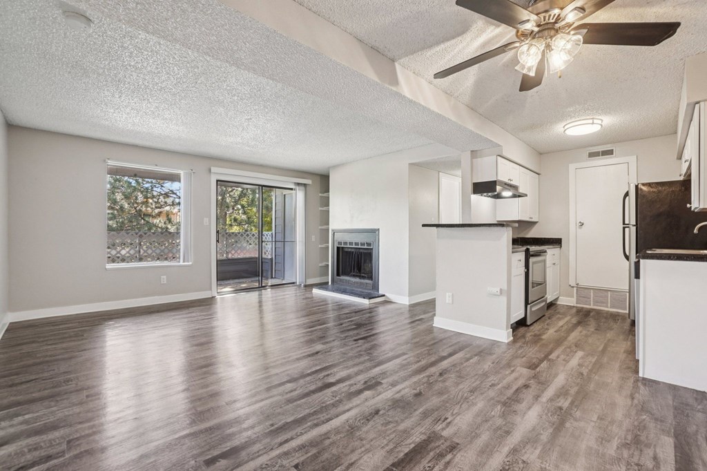 A spacious living room with a fireplace and a kitchen area in the background.