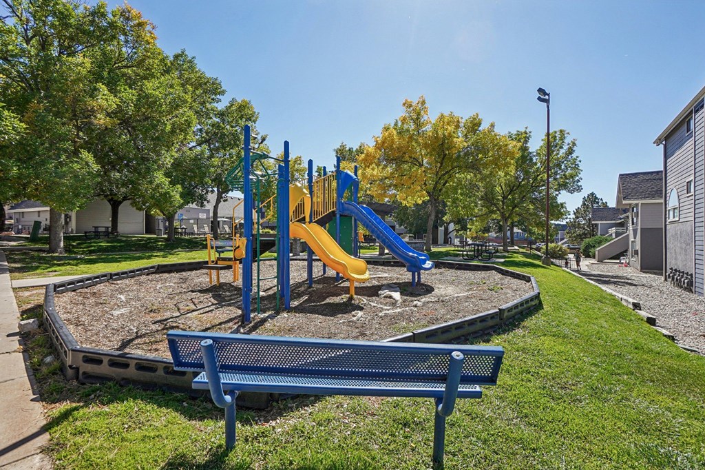 A playground with a blue bench and a yellow slide.