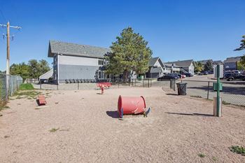 A playground with a red barrel and a grey building in the background.