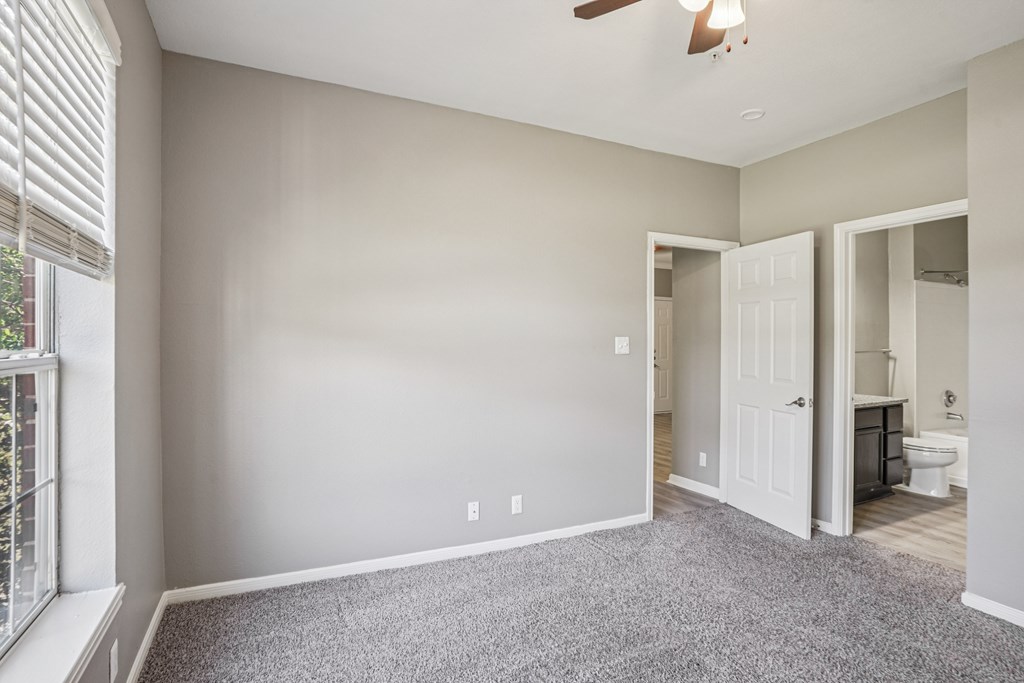 A room with a ceiling fan and a window with blinds.