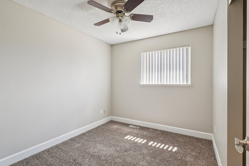 A room with a ceiling fan and a window with blinds.at Aspen Townhomes, Colorado Springs, CO