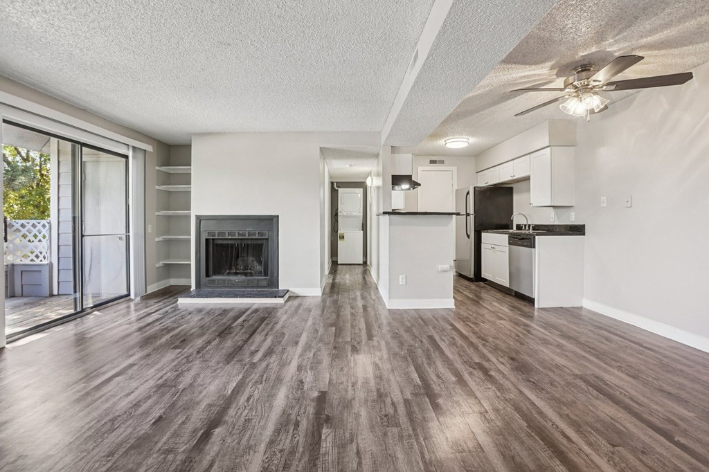 A spacious living room with wood flooring and a fireplace.