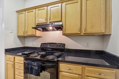 A kitchen with a black stove top and wooden cabinets.