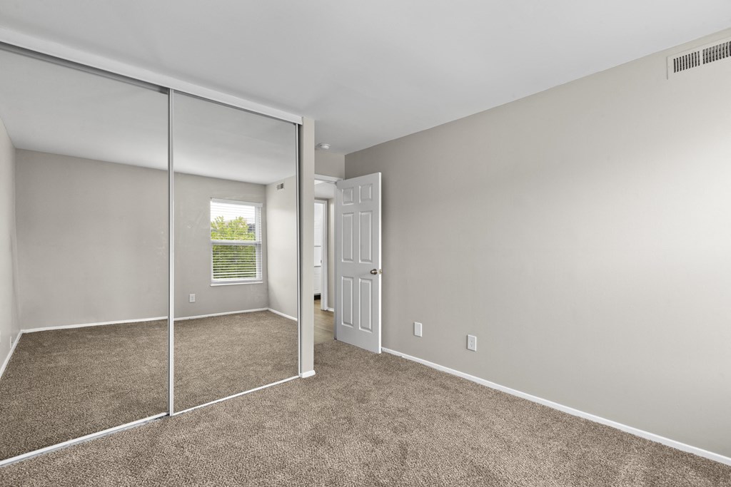 Bedroom with a mirrored closet and carpeted floors at Creve Coeur, Creve Coeur, MO