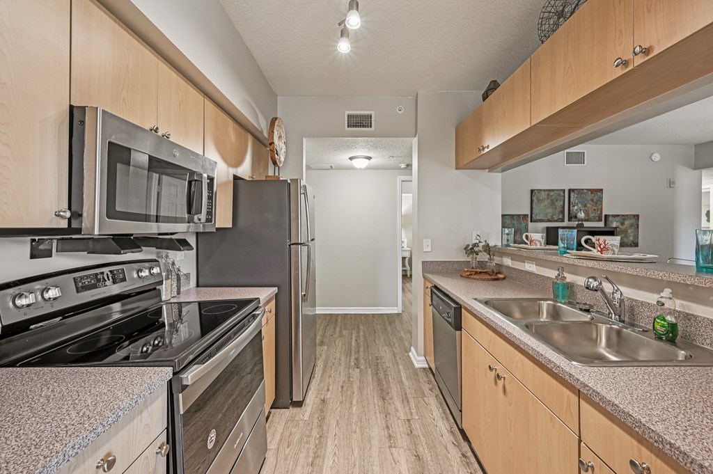 A kitchen with a stove, microwave, refrigerator, and sink. at Heritage Bay, Jensen Beach