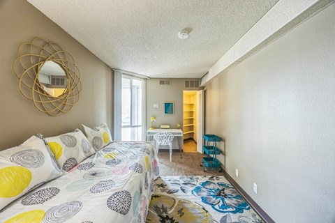 A bedroom with a bed, a chair, and a mirror.