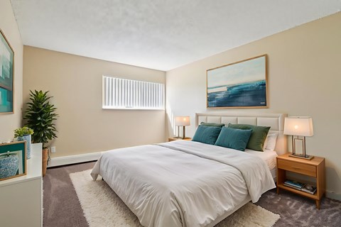 A bedroom with a large bed, a nightstand, and a painting on the wall.