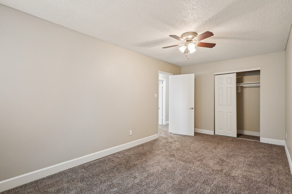 A room with a ceiling fan and carpeted floor.at Aspen Townhomes, Colorado Springs, CO