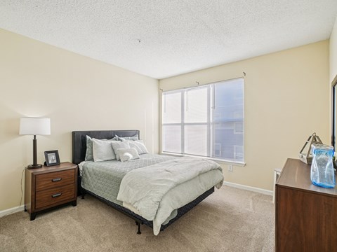 A bedroom with a bed, nightstand, and window.