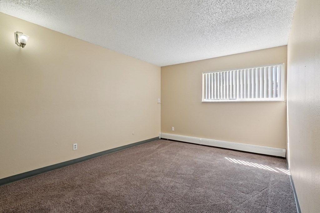 A room with a carpeted floor and a window with blinds. at Broadmoor Springs, Colorado Springs