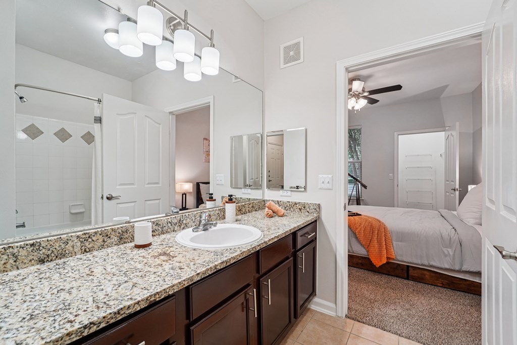 A bathroom with a marble countertop and a large mirror.at Kingwood Glen, Kingwood
