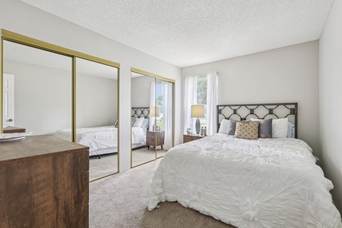 A bedroom with a large bed and a wooden dresser.