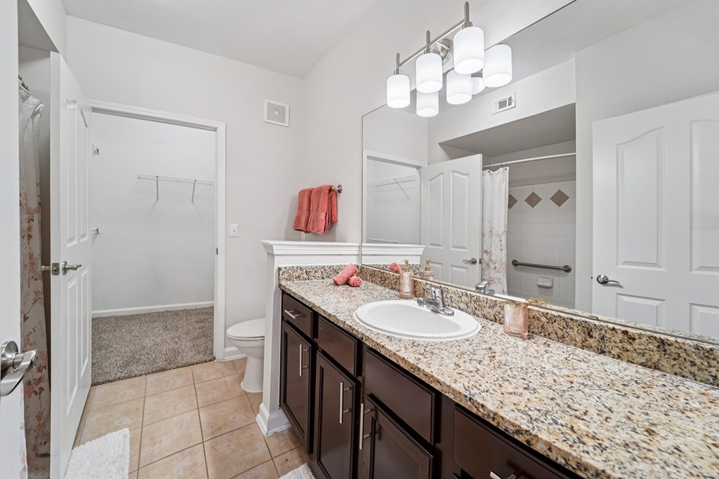 A bathroom with a granite countertop and a white sink.at Kingwood Glen, Kingwood