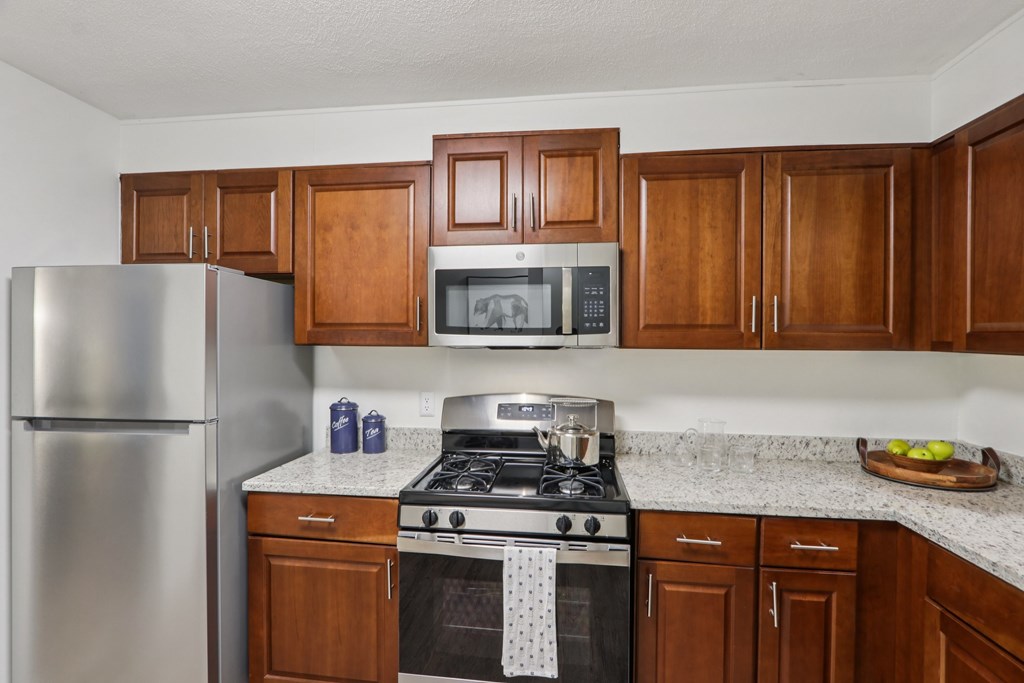 A kitchen with a stove, refrigerator, and cabinets. at Heritage at the River, Manchester, 03102