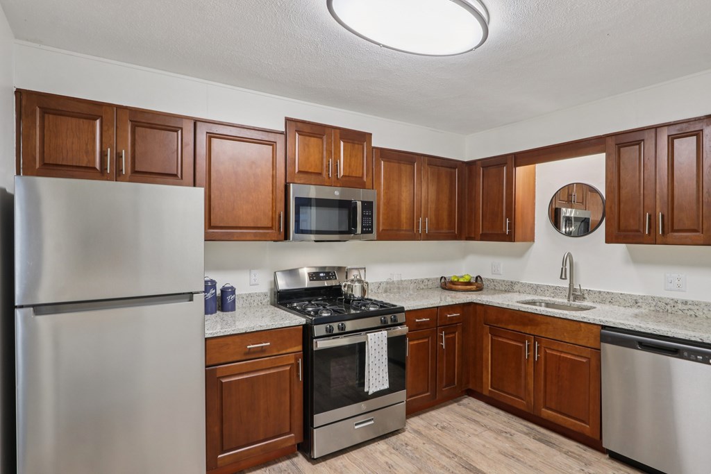 A kitchen with wooden cabinets and stainless steel appliances. at Heritage at the River, Manchester, New Hampshire