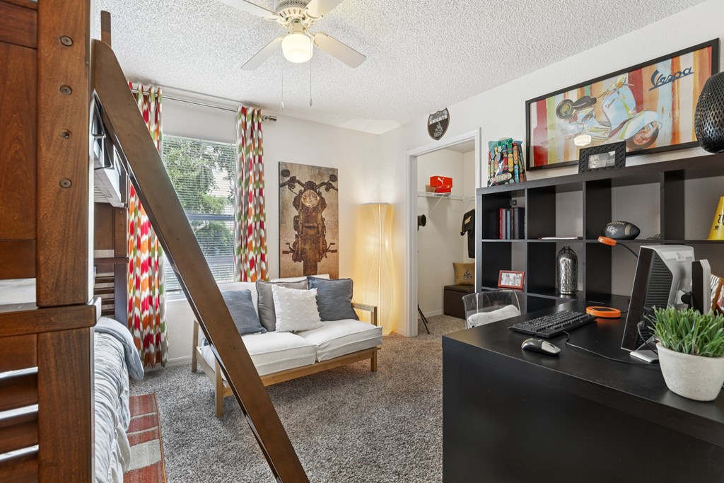 A living room with a couch, a chair, a desk, and a bookshelf. at University Park Apartments, Orlando, 32817