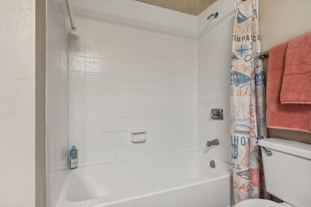a bathroom with a tub and a toilet and a shower curtain at The Glen at Highpoint, Dallas, 75243