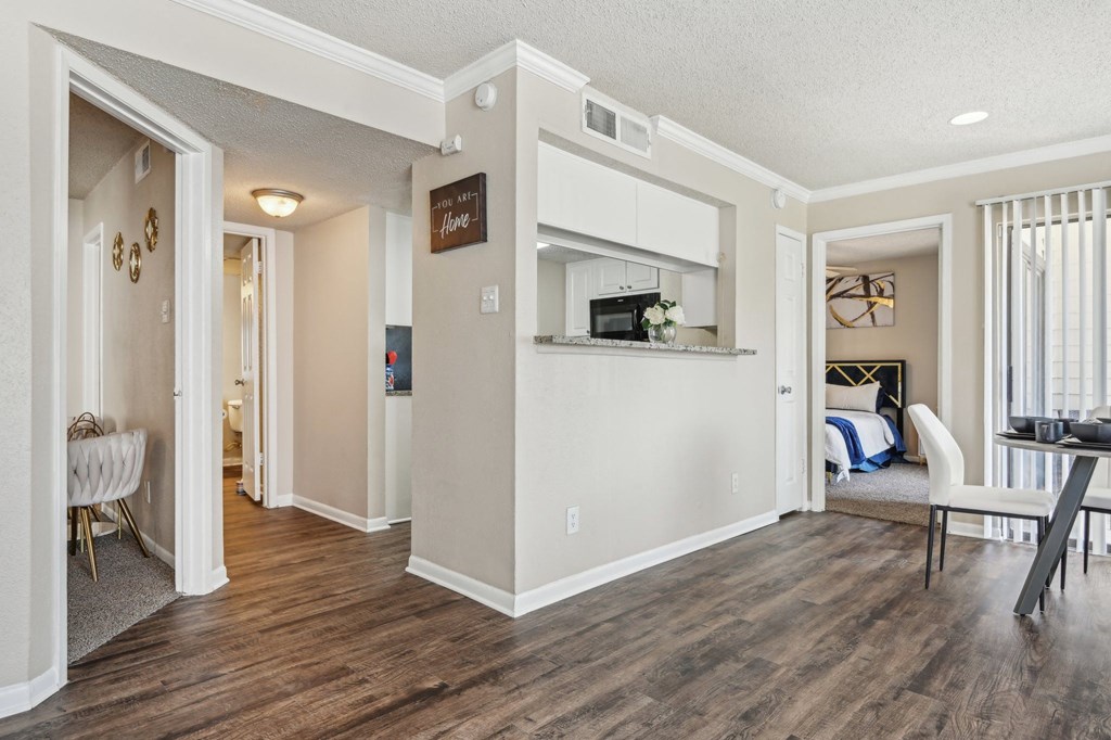 the living room and kitchen of a home with a hard wood floor at The Glen at Highpoint, Dallas, 75243