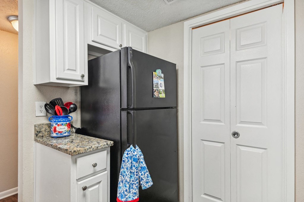 a kitchen with a black refrigerator and white cabinets at The Glen at Highpoint, Dallas, 75243