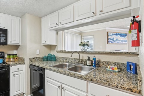 a kitchen with white cabinets and granite counter tops and a sink