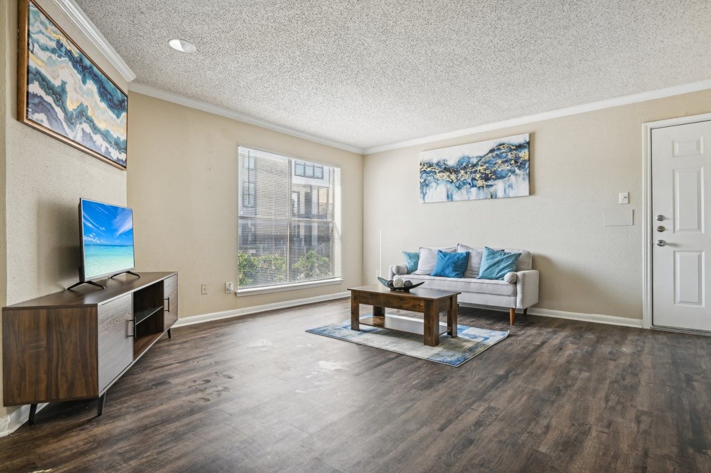 a living room with a couch and a table and a tv at The Glen at Highpoint, Dallas, 75243