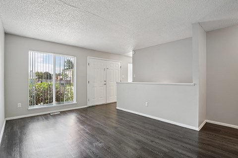 A spacious room with a view of a fence and trees through the window.