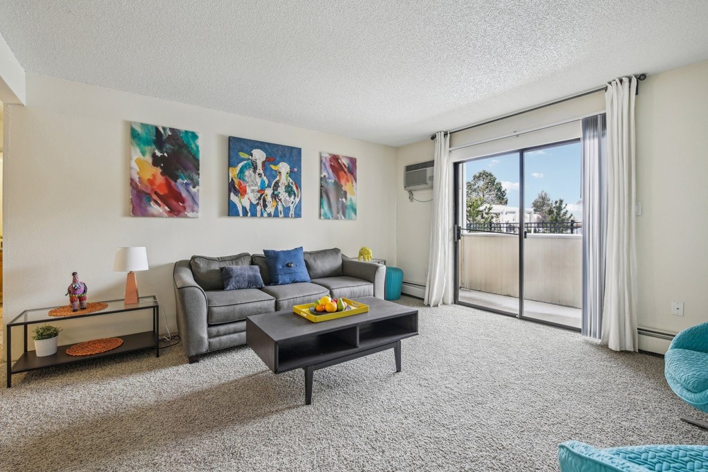 A living room with a grey couch, a coffee table, and two paintings on the wall at Spyglass Creek, Denver, 80224