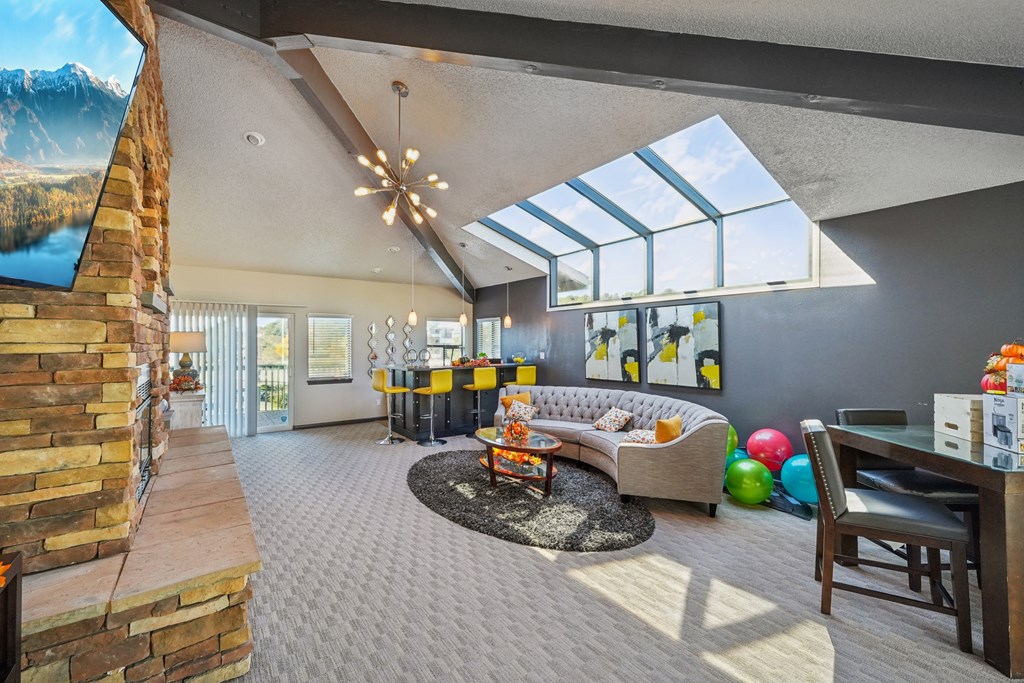 A living room with a stone fireplace and a skylight.