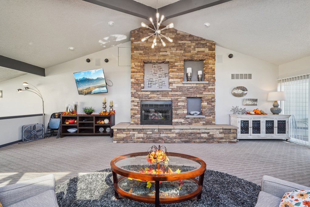 A modern living room with a stone fireplace and a television mounted on the wall.