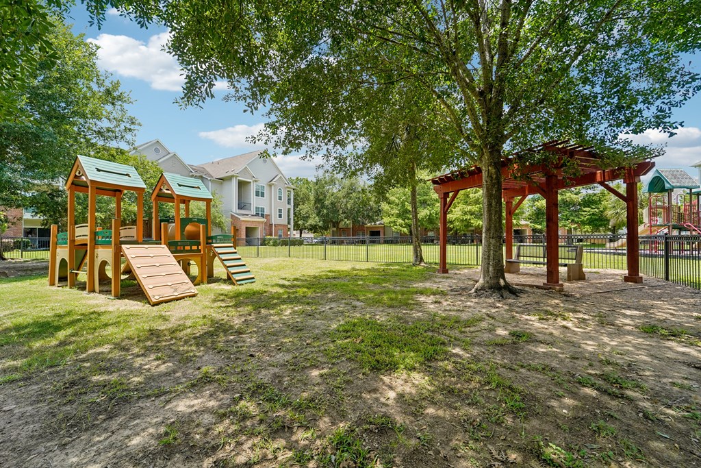A playground with a swing set and a treehouse in a park.at Kingwood Glen, Kingwood, 77339