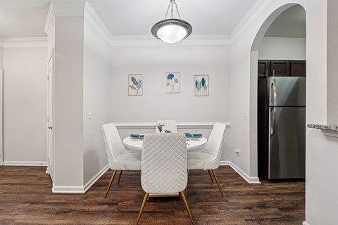 A dining room with a table set for two and a fridge in the corner.