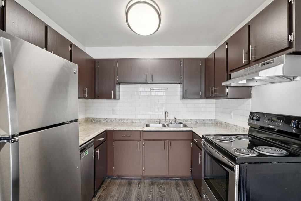 A kitchen with a refrigerator, oven, and sink.at Aspen Townhomes, Colorado Springs, 80909