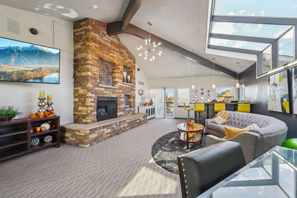 A living room with a stone fireplace and a flat screen TV mounted on the wall.