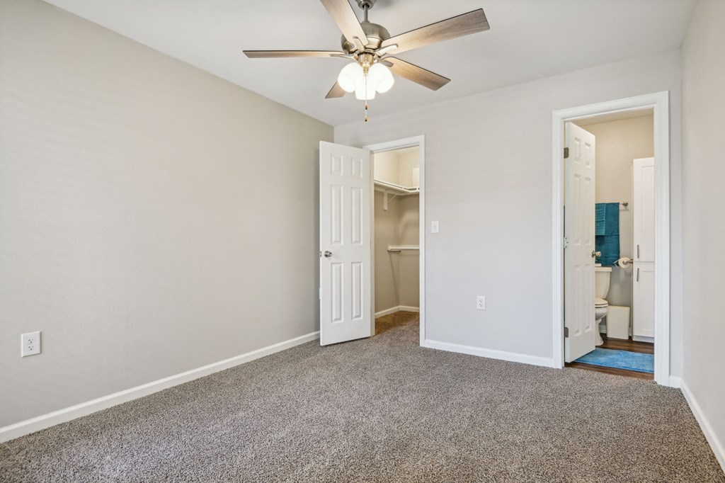 a bedroom with a ceiling fan and a door to a bathroom at The Glen at Highpoint, Dallas, 75243