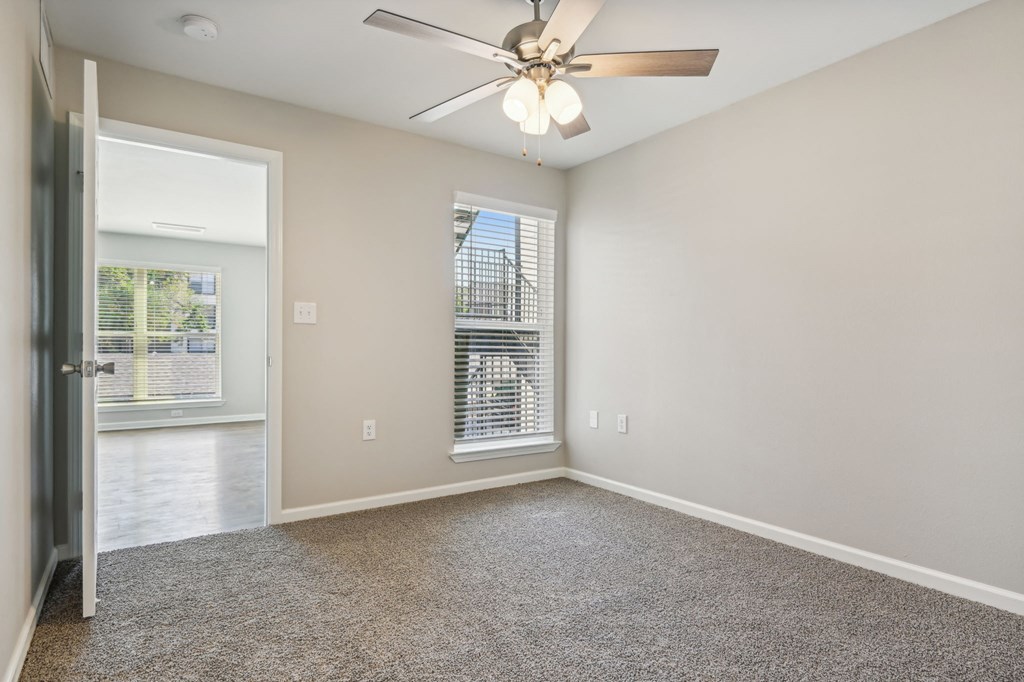 an empty living room with a ceiling fan and a window at The Glen at Highpoint, Dallas, 75243